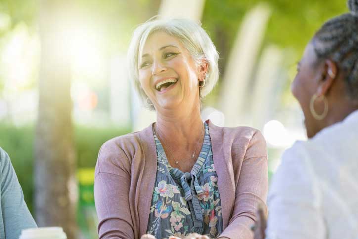 a senior woman sitting outside and laughing with friends