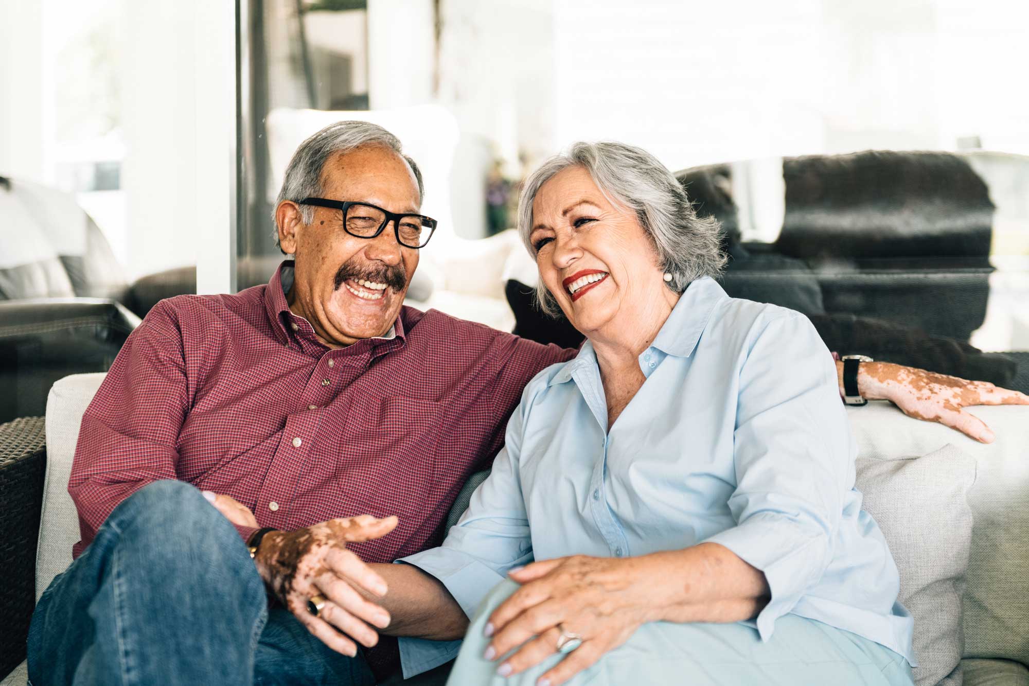 senior couple sitting on the couch laughing together